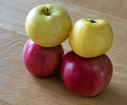 Two yellow and two red apples on a wooden table. Stock Photos