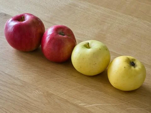 Two yellow and two red apples on a wooden table. Stock Photos
