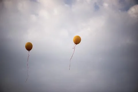 Two Yellow Balloons Floating In Cloudy Sky Stock Photos