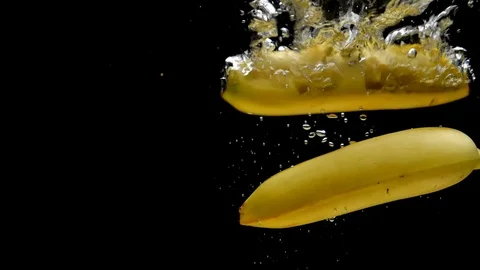 Two yellow bananas falling into transparent water on black background Stock Footage 108783948