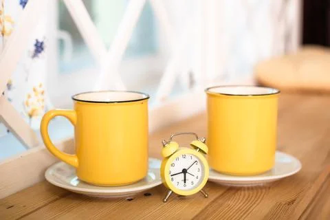 Two yellow cups with a clock in the middle Stock Photos
