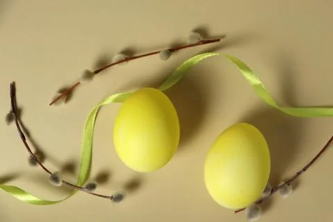 Two yellow eggs on a light background with green ribbon and floral elements Stock Photos