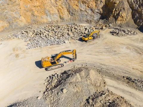 Two yellow excavators are operating on a construction site. They are moving l Stock Photos