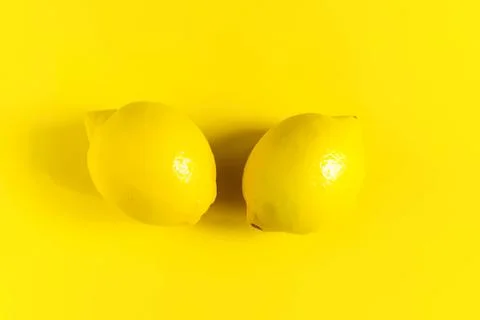 Two yellow lemons on a bright yellow background Stock Photos