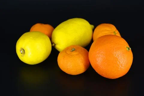 Two yellow lemons, three small orange mandarins, one large mineralola. Foto stock