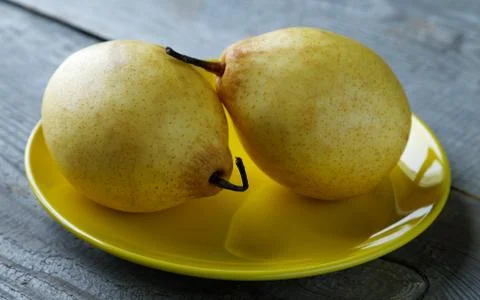 Two yellow pears on the plate on a rustic table Stock Photos