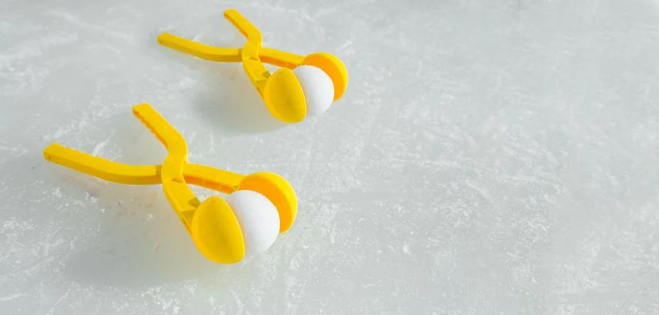Two yellow toy snowball Making tools are lying on an ice rink Stock Photos