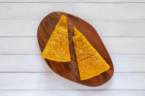 Two yellow triangular fruit pastille pieces with coconut flakes displayed o.. Stock Photos
