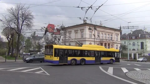 Two yellow/blue trolleybuses and a bus passing a junction near the railway stn. Stock Footage 64694847