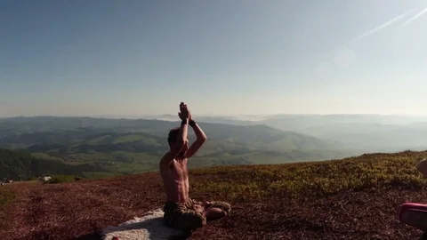 Two yoga men at the top of the mountains under the sun make asanas a summer day Stock Footage 77784977
