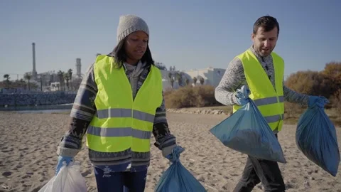 Two young activists chatting and walking holding garbage bags. Concept of Stock Footage 234112968