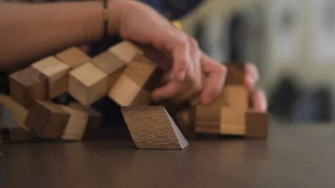 Two young adult hands solving a interlocking wooden puzzle game. Video stock 104395534