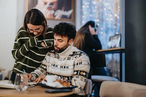 Two young adults engaging in collaborative work in a cafe with warm ambient Foto stock