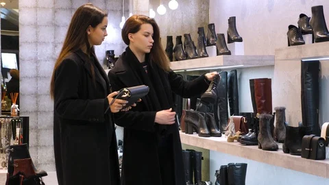 Two young adults trying to chose shoes, bag in the shopping mall Stock Footage 99664616