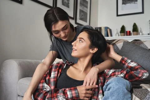 Two young affectionate gen z women in love embracing at home. Stock Photos