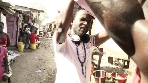 Two young African guys pick up a heavy bag of rice, put it on the head of one of Stock Footage 168879223