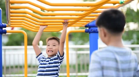Two young asian boy hang the yellow bar by his hand to exercise at out door play Vídeos de archivo 64749892