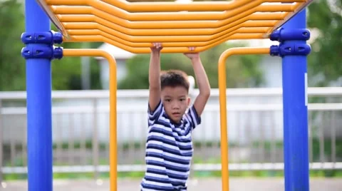 Two young asian boy hang the yellow bar by his hand to exercise at out door play 库存影片 64816830