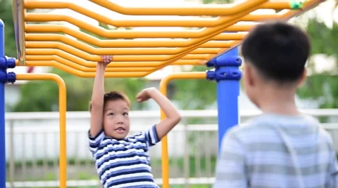 Two young asian boy hang the yellow bar by his hand to exercise at out door play Stock Footage 66420963