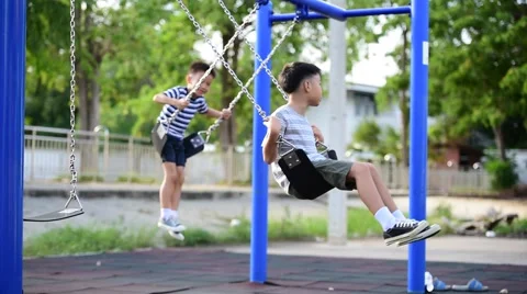 Two young asian boy play a iron chain swinging at the playground  库存影片 64816733