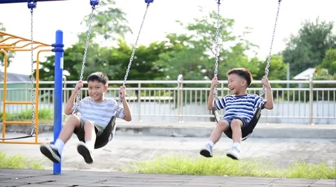 Two young asian boy play a iron chain swinging at the playground  Stock Footage 65310602