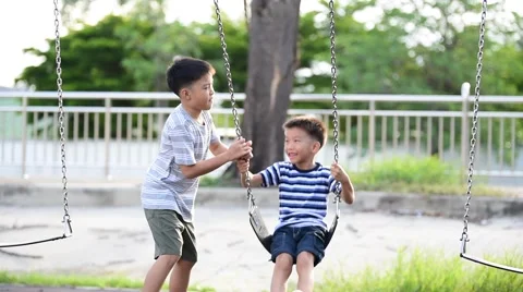 Two young asian boy play a iron chain swinging at the playground  库存影片 65310613
