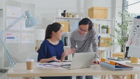 Two young Asian startup partners are working in a casual small business office. Stock Footage 253366252