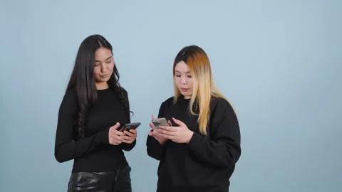 Two Young Asian Women Using Smartphones against Studio Background Vídeo Stock 346111133