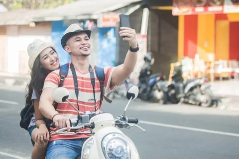 Two young backpackers taking selfies using mobilephones camera w Stock Photos