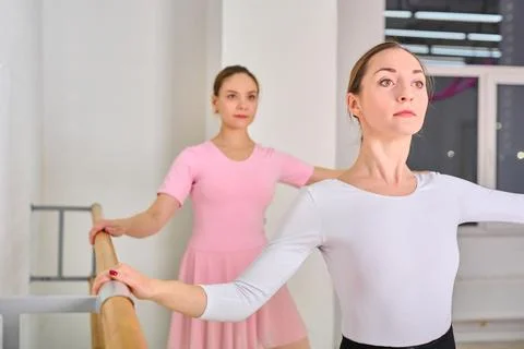 Two young ballerinas practicing at ballet barre in studio setting Stock Photos