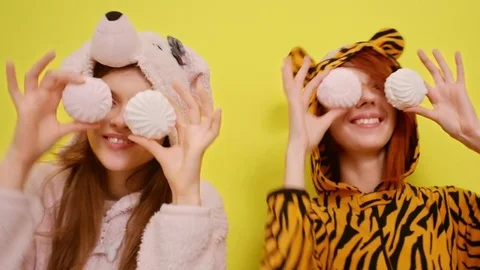 Two young beautiful happy smiling girls jump, dance, hide eyes with round Stock Footage 77262481