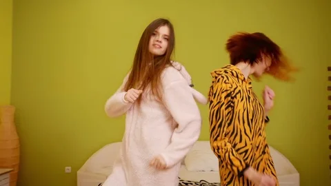 Two young beautiful happy smiling girls jump, dance. Models wear funny kigurumi Stock Footage 77265823