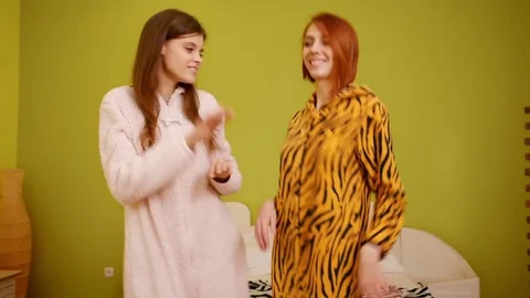 Two young beautiful happy smiling girls jump, dance. Models wear funny kigurumi Stock Footage 77266067