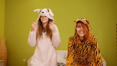 Two young beautiful happy smiling girls jump, dance. Models wear funny kigurumi Vídeo Stock 77266319