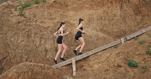 Two young beautiful ladies do some sport and jog up the stairs, in the nature Stock Footage 115175547