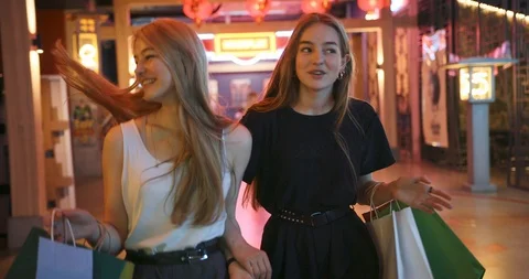 Two young beautiful lady walking after successful shopping, they smile and carry Stock Footage 112688451
