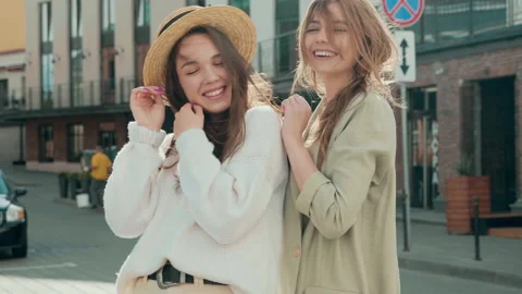 Two young beautiful smiling hipster girls in trendy white sweater and coat Stock Footage 142522932