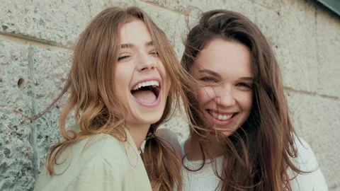 Two young beautiful smiling hipster girls in trendy white sweater and coat Stock Footage 142523760
