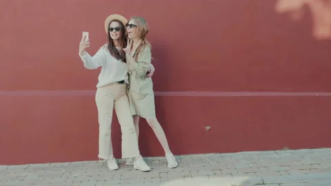Two young beautiful smiling hipster girls in trendy white sweater and coat Stock Footage 142524948