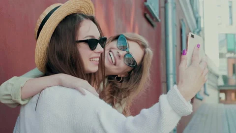 Two young beautiful smiling hipster girls in trendy white sweater and coat Stock Footage 142525193