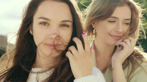Two young beautiful smiling hipster girls in trendy white sweater and coat Stock Footage 142556033