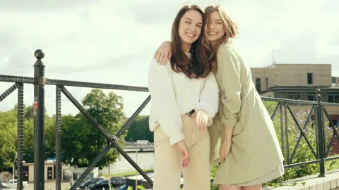 Two young beautiful smiling hipster girls in trendy white sweater and coat Stock Footage 142556293