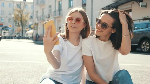 Two young beautiful smiling hipster female in trendy summer clothes Stock Footage 154904401