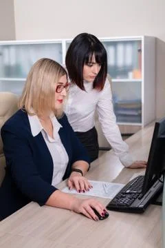 Two young beautiful weman work in the office. Copmuter teamwork. Foto stock