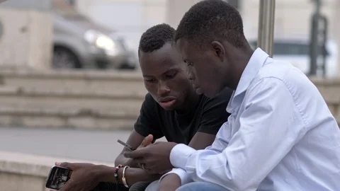 Two young black african using smartphone sitting in the city Stock-Footage 92391018