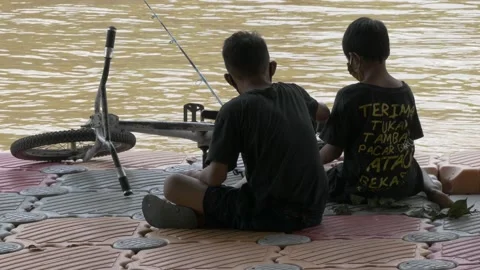 Two young boy fishing in the river, sitting on the floating deck Stock Footage 157162186