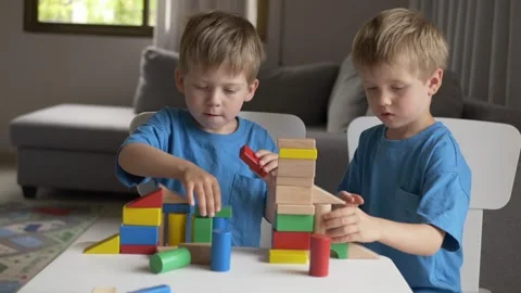 Two young boys enjoy playing with wooden geometric blocks, stacking towers and Stock-Footage 317318259