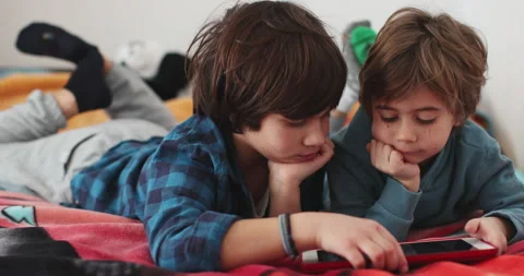 Two young boys laying on bed looking at tablet Stock Footage 274227887