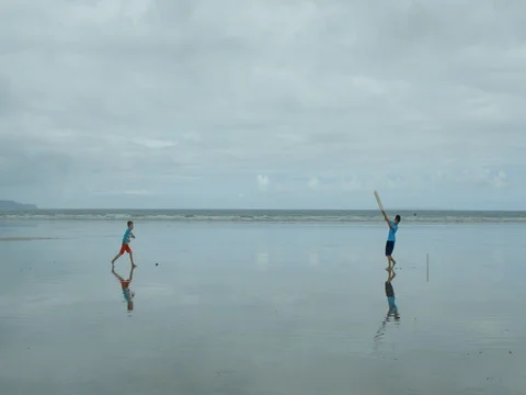 Two young boys playing Beach Cricket. Video stock 79797010