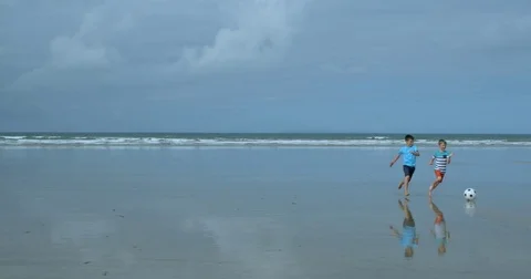 Two Young Boys Playing Soccer on a beach running for the ball in Slow Motion. Vídeo Stock 79792556
